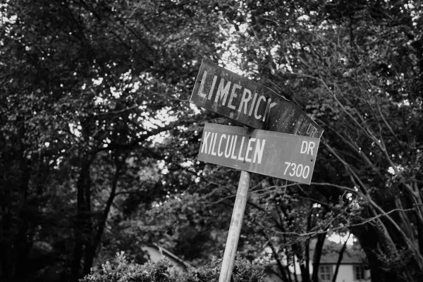 two street signs with the top one being banged up