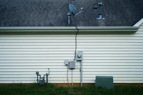 the side of a house with electrical meters and a satelight dish on the roof