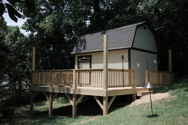 a large shed sits in a back yard surrounded by a deck