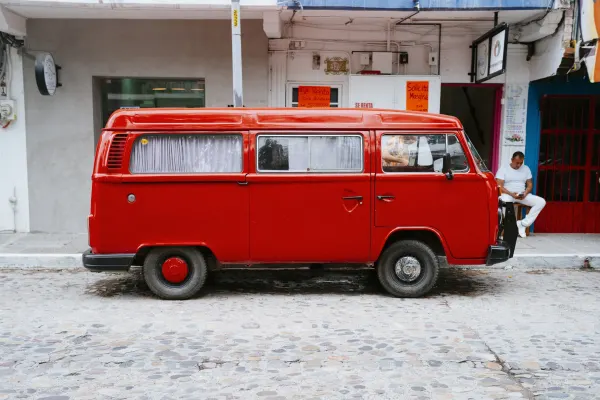 The profile of a bright, firetruck red Volkswagen van parked on the street
