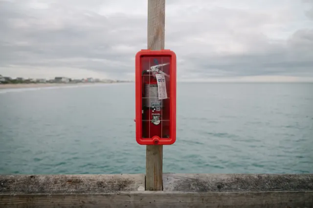 an emergency fire extinguisher mounted on a post of a wooden pier