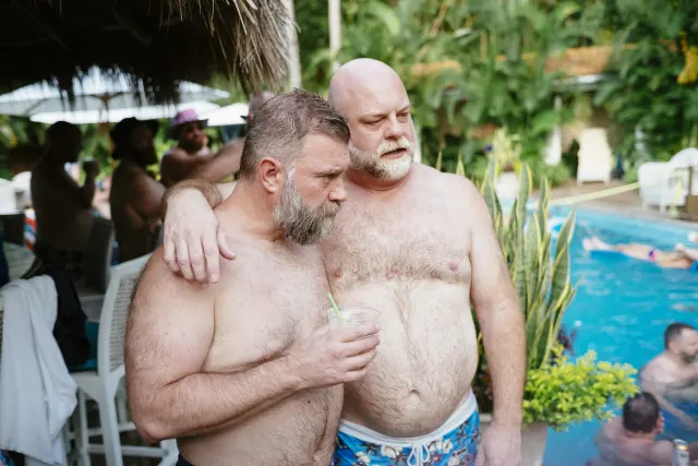 Two men discussing the drinking games. A swimming pool in the background.
