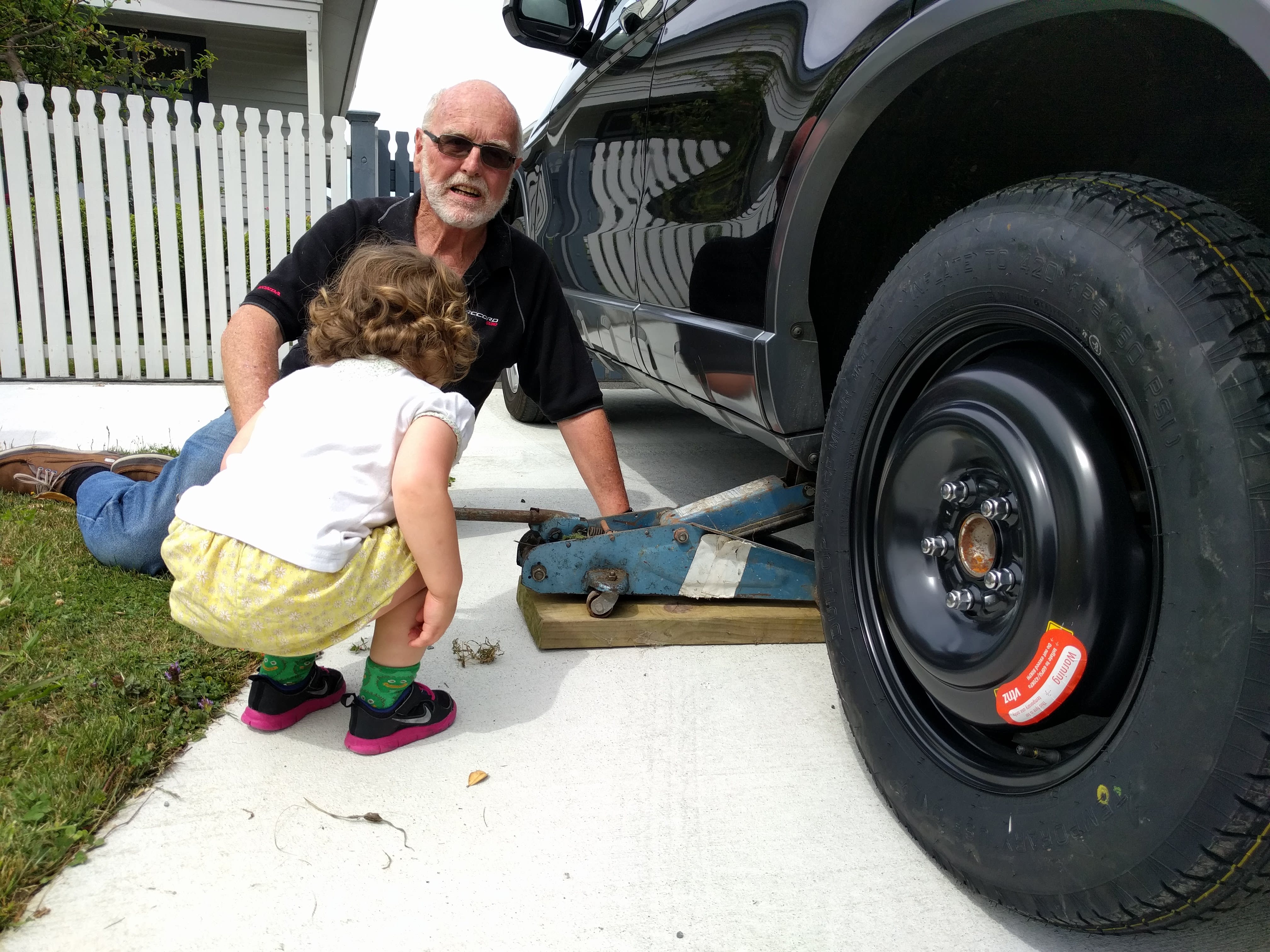 Granddad assisting Karolina with the wheel change.