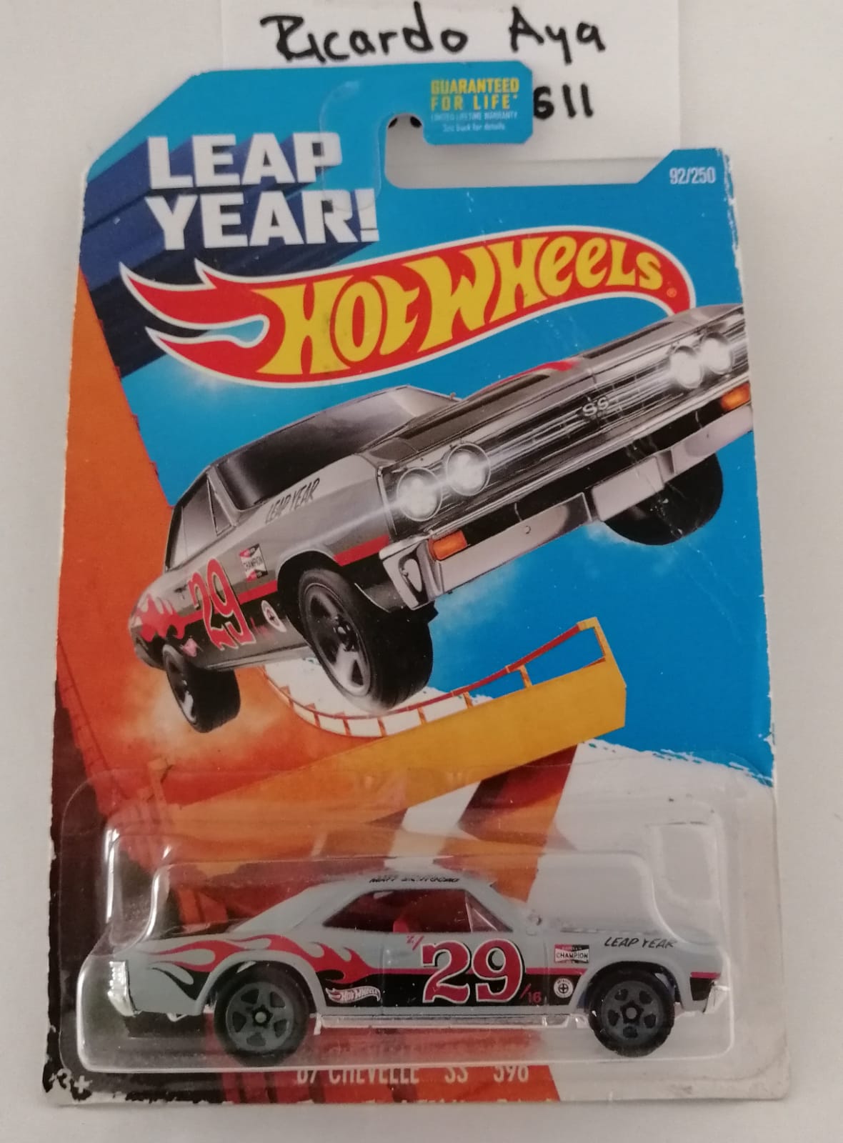 Front of satchel with blue canvas body, black straps and handle, drawstring top, and front zipper pouch.