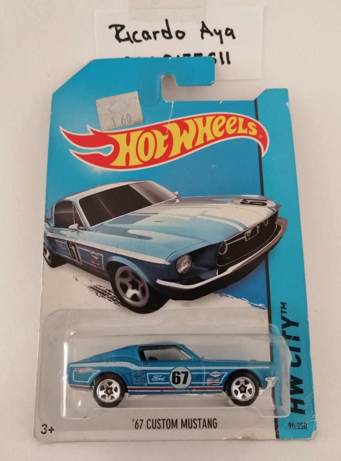 Front of satchel with blue canvas body, black straps and handle, drawstring top, and front zipper pouch.