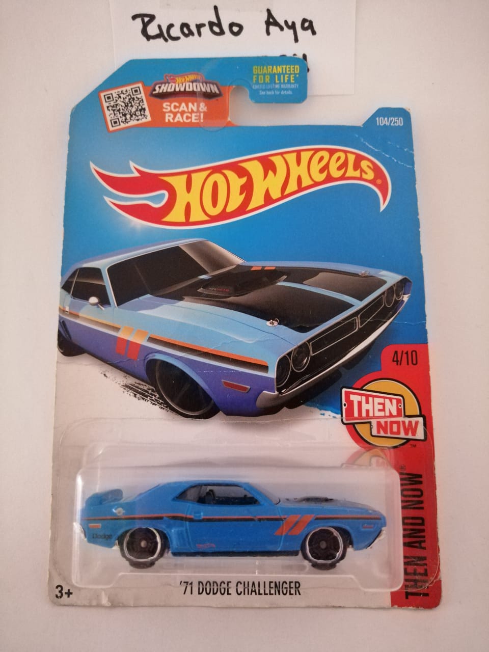 Front of satchel with blue canvas body, black straps and handle, drawstring top, and front zipper pouch.