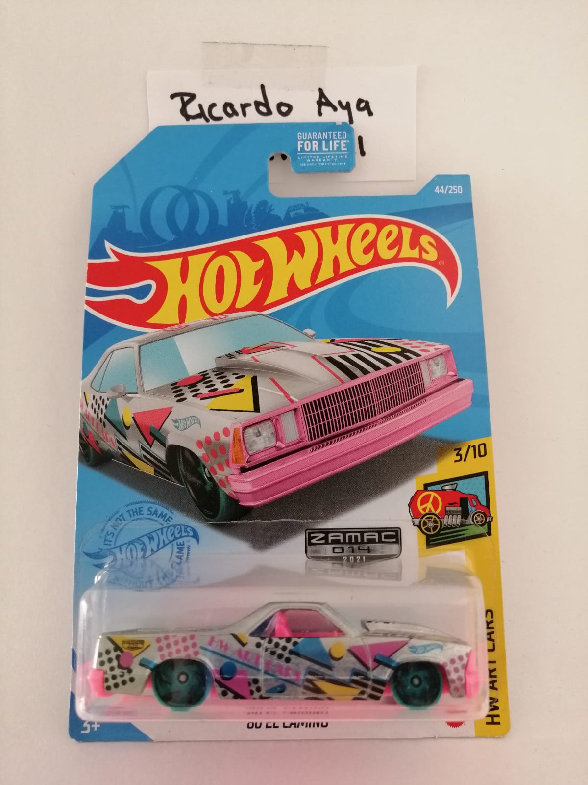 Front of satchel with blue canvas body, black straps and handle, drawstring top, and front zipper pouch.