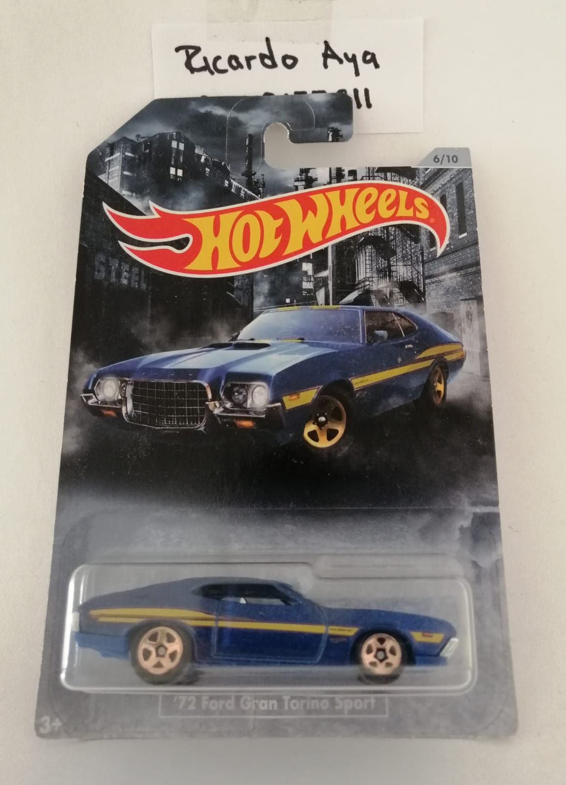 Front of satchel with blue canvas body, black straps and handle, drawstring top, and front zipper pouch.