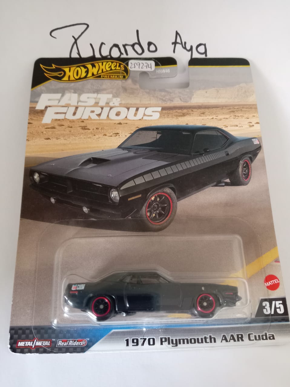 Front of satchel with blue canvas body, black straps and handle, drawstring top, and front zipper pouch.