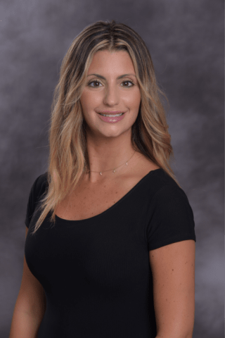 Stephanie Nask, an advanced practice provider, wearing a black shirt and gold necklace smiling into the camera.