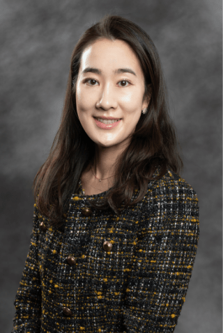Dr. Hyun Jin (Angela) Lim wearing a black, white, and yellow blazer smiling into the camera.