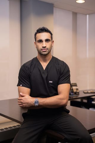 Dr. Chaitan Devulapalli looking into the camera while sitting on a table,