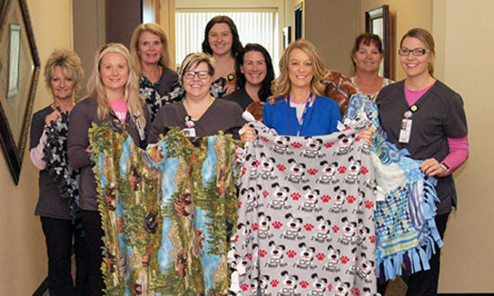 Lake Regional Health System Diagnostic Imaging staff pose with handmade blankets for Lake Regional Cancer Center patients. Pictured are, left to right, Pam Walters RT(R)(M)(QM)(BD); Katelynn Holdt, RT(R)(T)(CT); Karen Bischof RT(R)(MR); Rogetta Meyer, RT(R)(M)(BD); Amanda Blaeuer; Kristy Wood, RT(R)(M); Heather Koch, R.N.; Kari Hartema, CHAA; and Mandy Bargfrede, RT(R)(M).