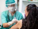 A healthcare worker swabs a woman's shoulder.