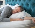 A man sleeps on his side in bed.