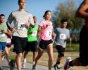 Runners wearing numbers jog in a road race.