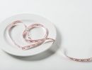 A fabric tape measure draped on an empty plate in the shape of a heart
