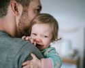 A man holds a smiling baby.