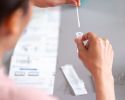 A person holds a swab above a test tube.