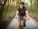 A man rides a bike on a tree-lined path.