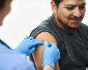 A nurse places a circular bandage on a man’s upper arm.