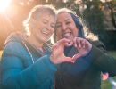 Two women form a heart with their combined hands.
