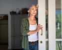 An older woman looks pensively out her sliding door