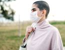 A woman in a face masks walks down a sidewalk.