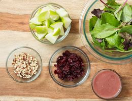 Ingredients for apple salad spread out in bowls.