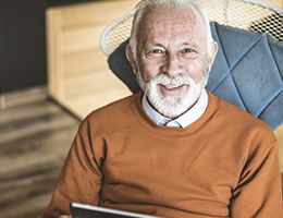 An older man smiles at the camera