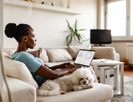 A woman on a couch works on her laptop.