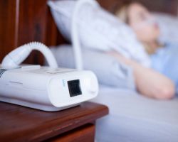 A CPAP machine in front of a person sleeping in bed.