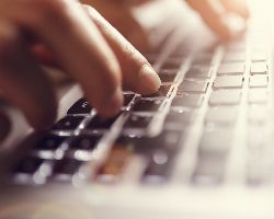 Hands typing on a computer keyboard.