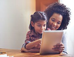 A woman and child look at a tablet together.