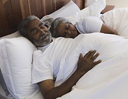 A man and woman sleeping in a bed.