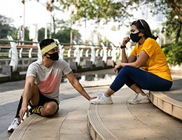 Two friends sit on steps in a public park.