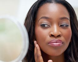 A woman viewing her hair in a mirror.