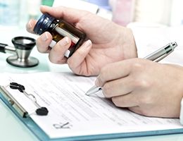 A doctor writing on a prescription pad.