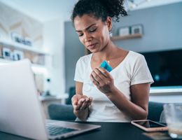 A woman putting on hand sanitizer at her desk.
