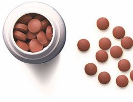 A bird's-eye view of a pill bottle and some pills on a table.