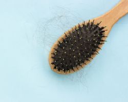 A wooden hairbrush with some strands of hair.