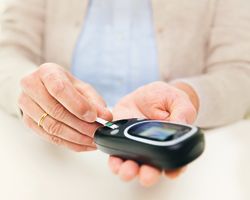 Hands insert a test strip into a glucose monitor.