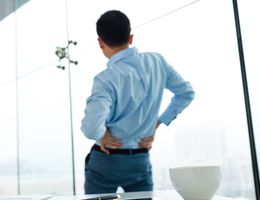 A man stretches with his hands on his lower back