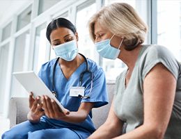 A patient and a healthcare provider look at a tablet together.