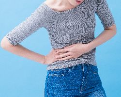 A woman grips her stomach in pain.