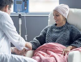 A woman in a chemotherapy chair receives an infusion.