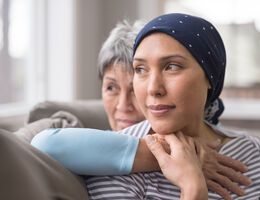 An older woman hugs a younger woman wearing a headscarf