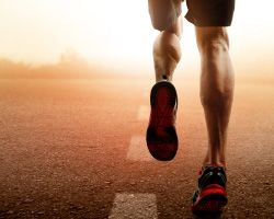 A runner on a track moving away, shown from the thighs down