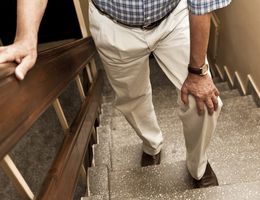 Halfway up a flight of stairs, a man rests with his hand on his knee