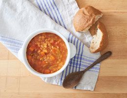 Lentil soup with crusty bread and a wooden spoon.